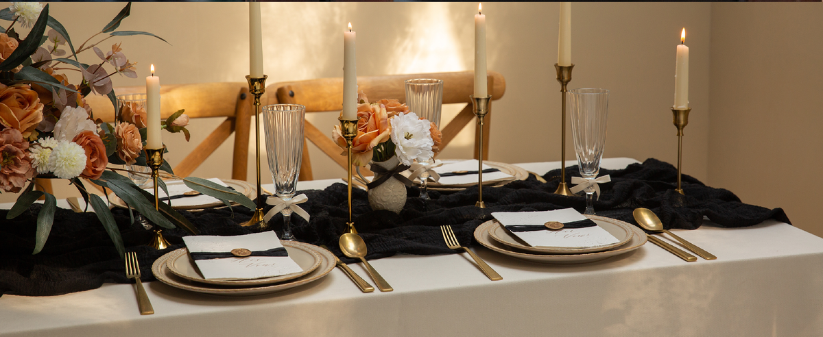 Black, gray, and white velvet ribbon set styled across a dining table with flowers, candles, and place settings