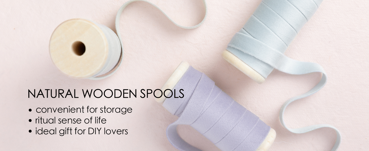 Blue and purple velvet ribbon set unwound from natural wooden spools in a clean product detail scene