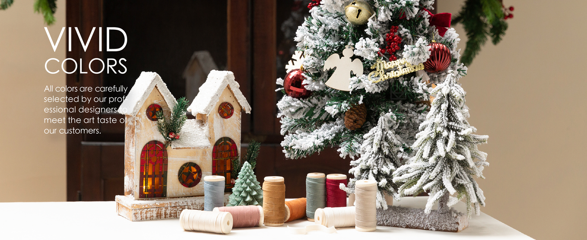 Mixed-color velvet ribbon spools displayed beside a snowy Christmas tree decorated with bright red ribbon bows.