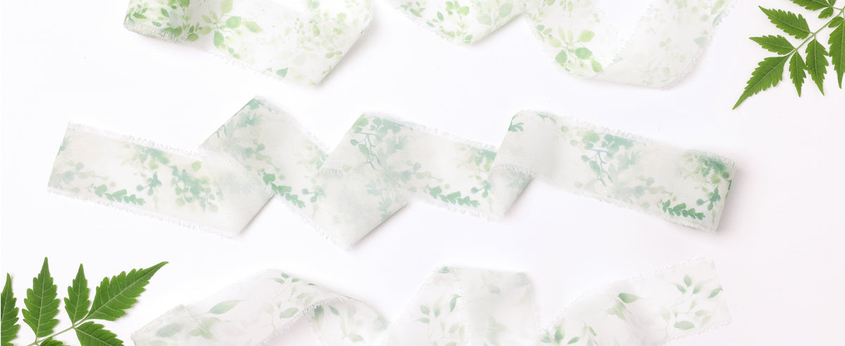 Three white translucent frayed ribbons with varied pale green botanical patterns