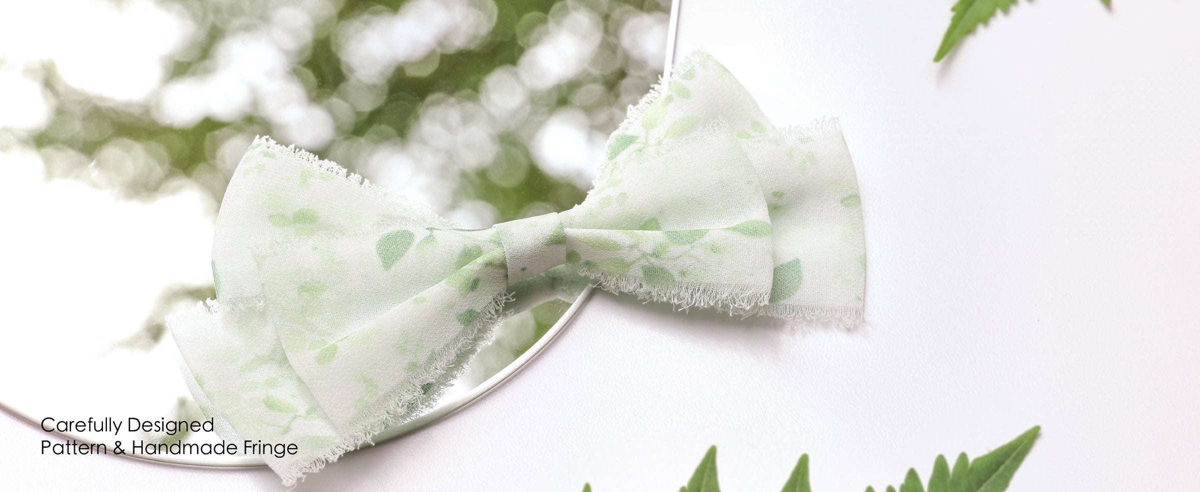 Green leaf-print frayed ribbon tied around a blush bouquet and a white chair arrangement