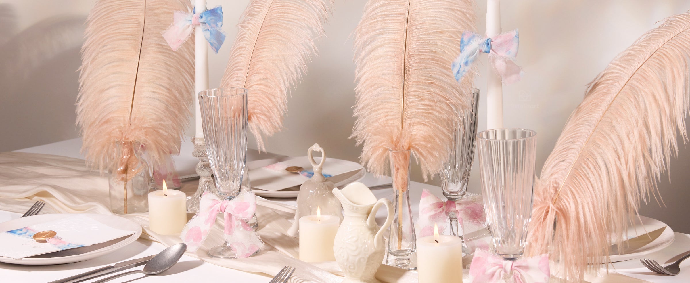 Pastel pink and blue frayed chiffon ribbon bows decorating candles and glassware on an elegant table