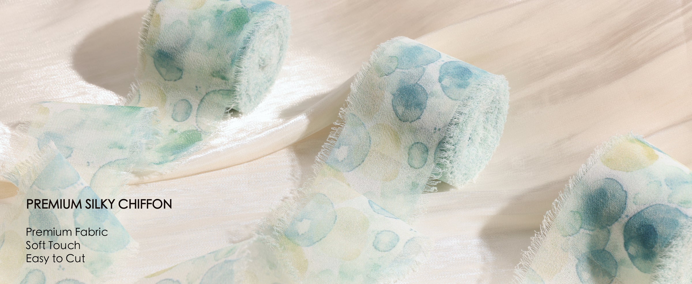 Aqua circle-print silky chiffon ribbon rolls with sheer fabric and soft frayed edges on cream satin