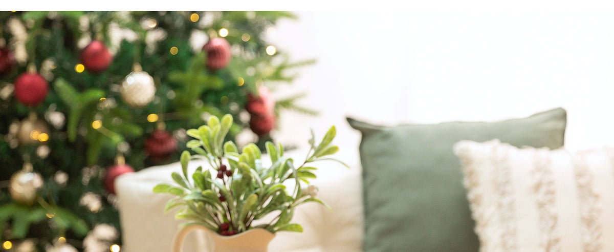 Deep red velvet bows decorating frosted greenery and a snowy Christmas wreath with berries and pinecones