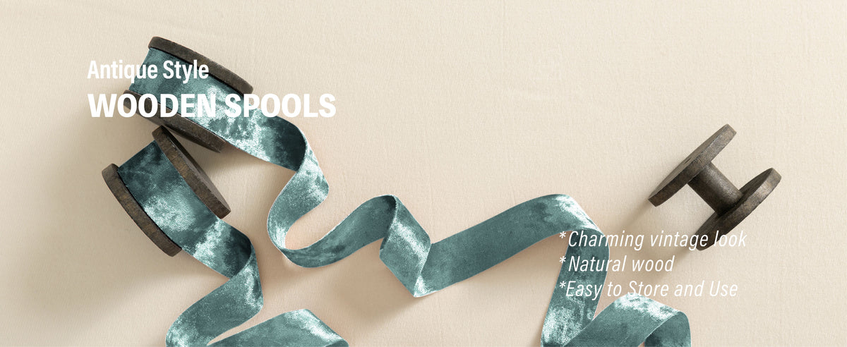 Pale blue crushed velvet ribbon flowing from dark antique-style wooden spools on cream fabric