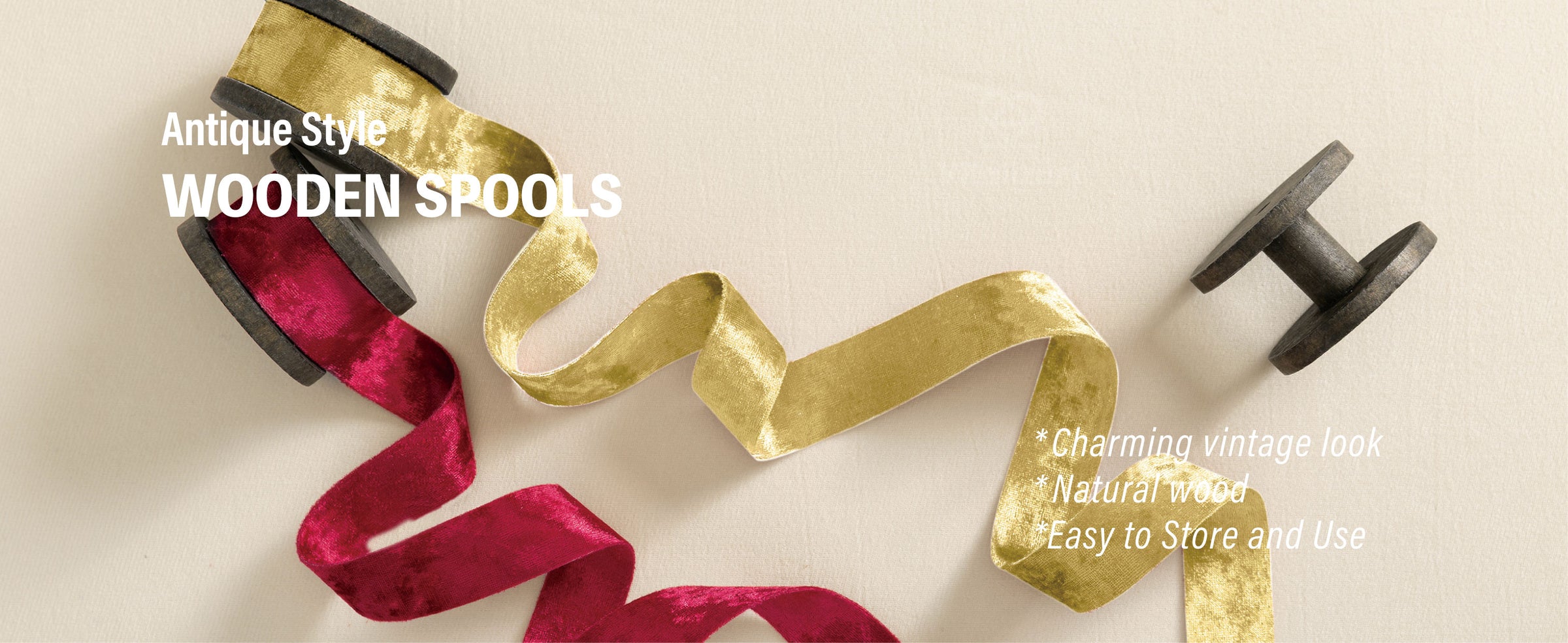 Gold and deep red velvet ribbons unrolled from antique-style dark wooden spools on cream fabric