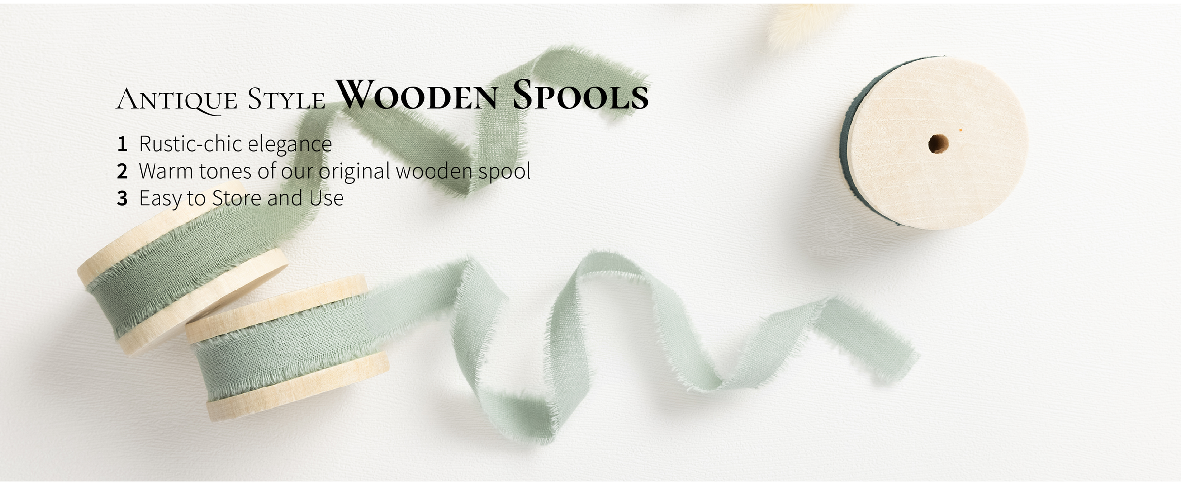 Sage and dark green frayed cotton ribbons unwind from three antique-style wooden spools