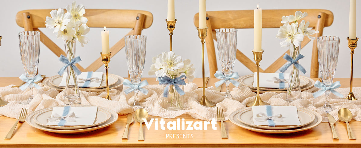 Pale blue fringed cotton ribbon decorates vases, glasses, and place settings on an elegant dining table.