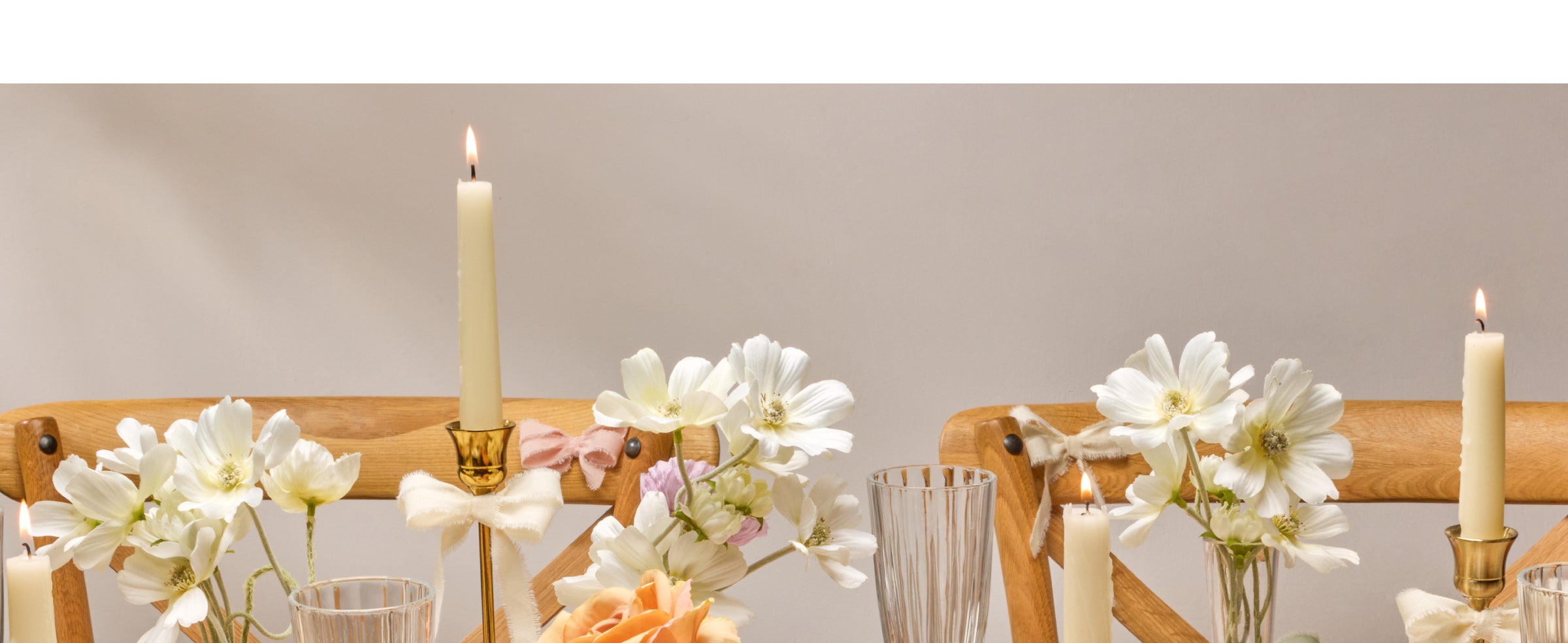 Pale pink fringed cotton ribbon tied in bows around a flower vase and a textured invitation.