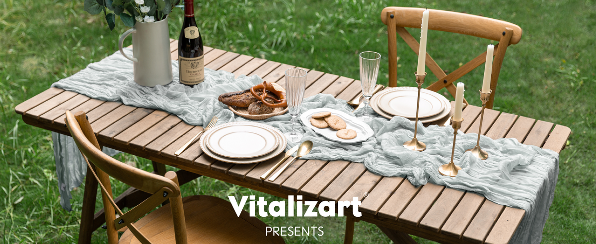 Gray-blue cheesecloth table runner styled with candles and place settings on an outdoor wooden table