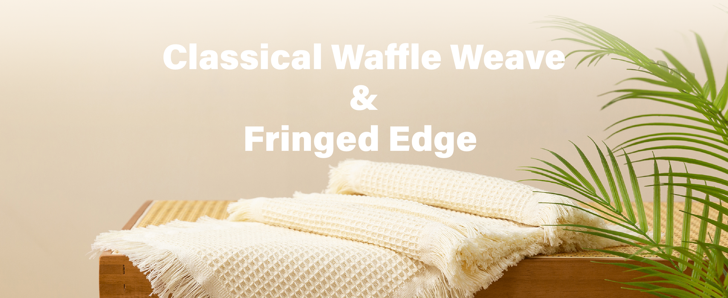 Folded cream waffle-weave table runners with fringed edges stacked on a wooden bench