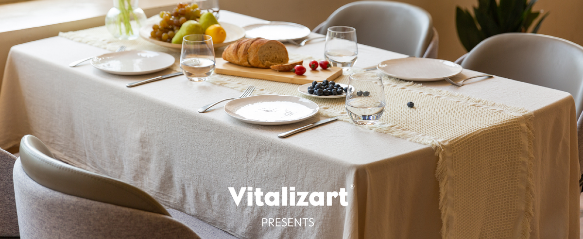 Cream fringed waffle-weave table runner on a sunlit dining table set with bread, fruit, and flowers