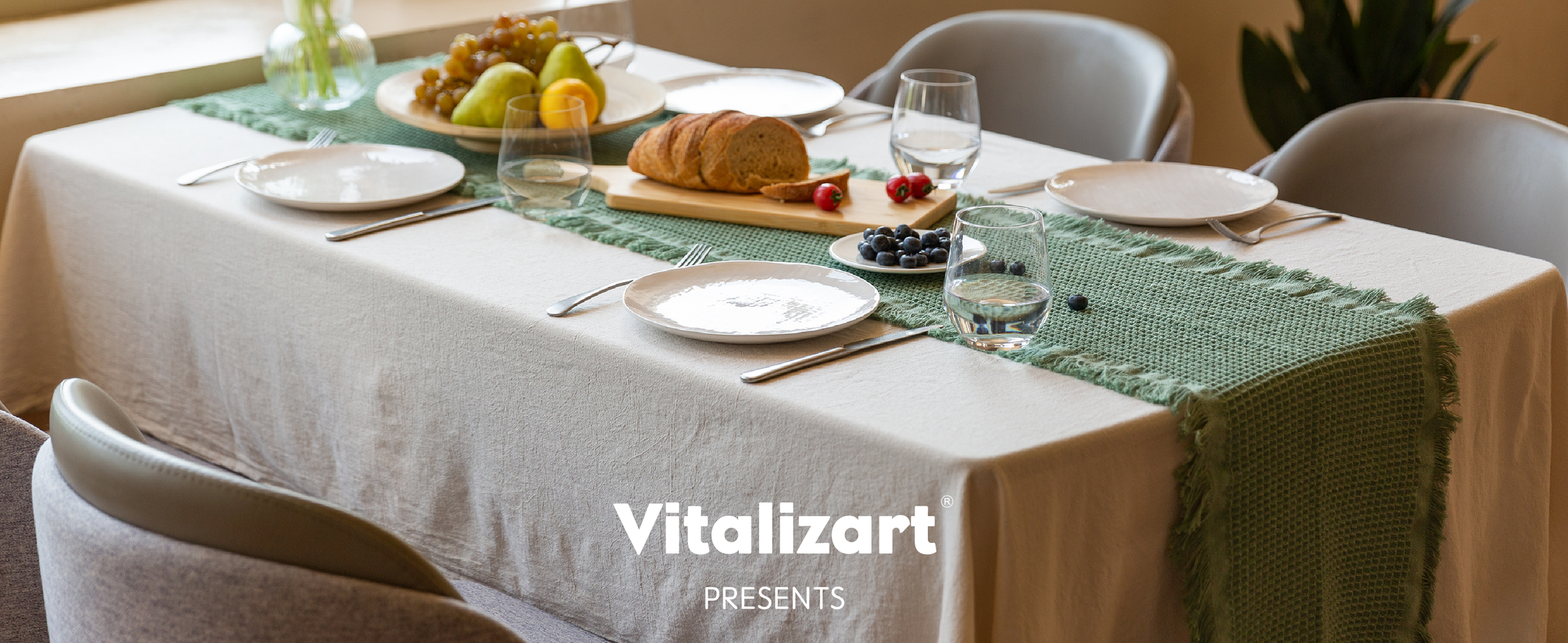 Dusty green waffle-weave table runner styled on a sunlit dining table with bread, fruit, and flowers.