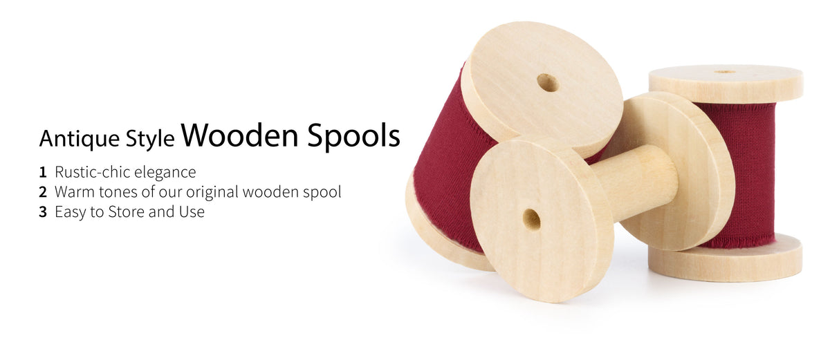 Burgundy fringed cotton ribbon wound on pale wooden spools, with one empty spool in front.