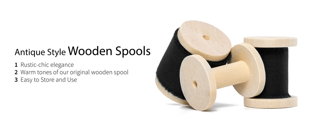 Two rolls of black frayed cotton ribbon and an empty pale wooden spool displayed on white