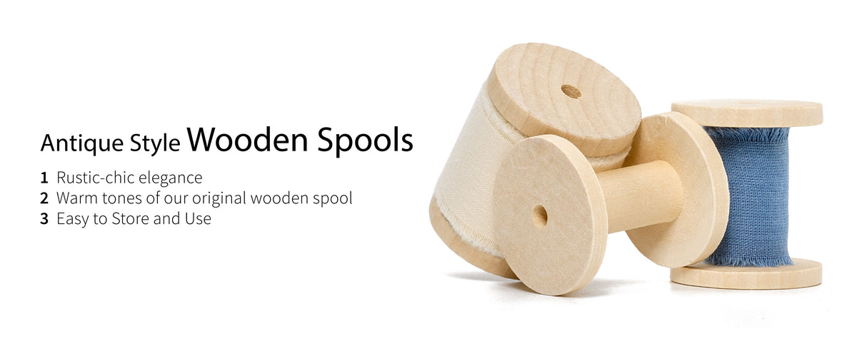 Blue and cream frayed-edge cotton ribbons on pale antique-style wooden spools beside an empty spool