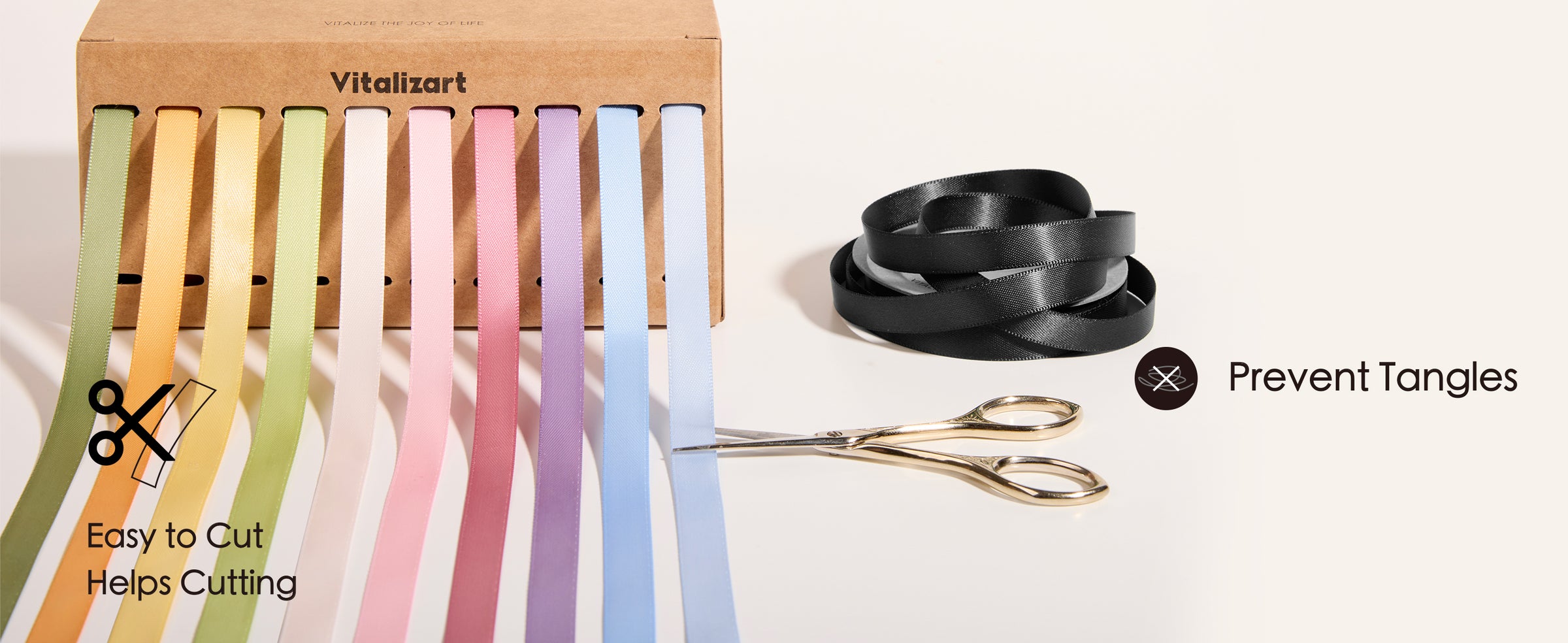 Pastel satin ribbons feed from a dispenser box beside scissors and a loose ribbon coil