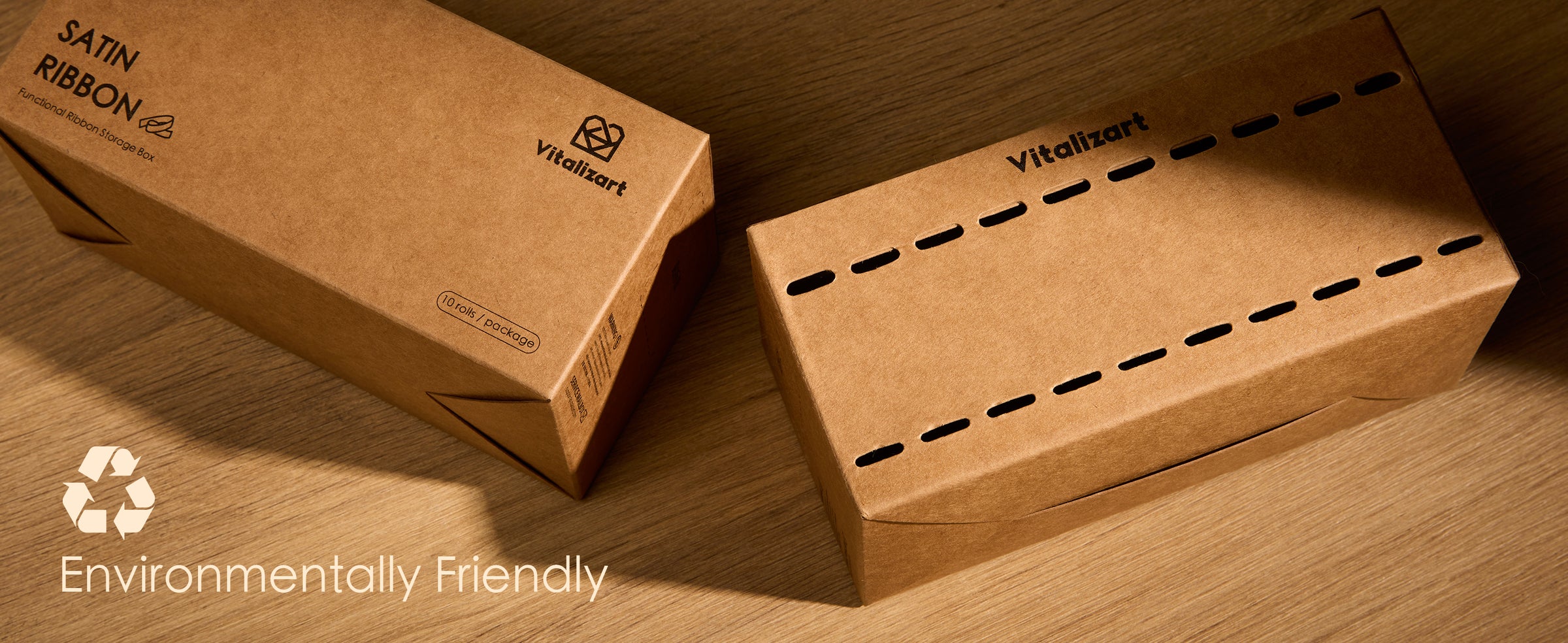 Two brown cardboard ribbon dispenser boxes with slot openings on a wooden surface