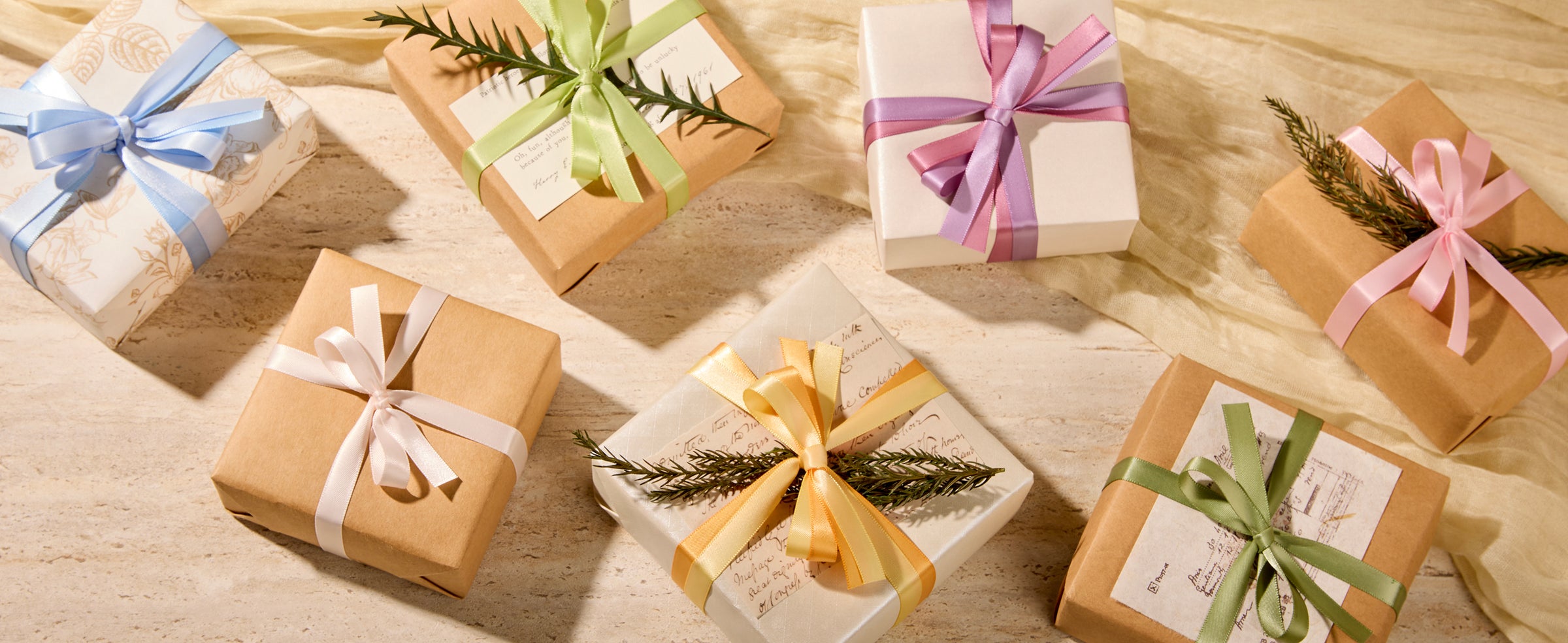 Gift boxes tied with pastel satin ribbon bows and greenery in warm sunlight