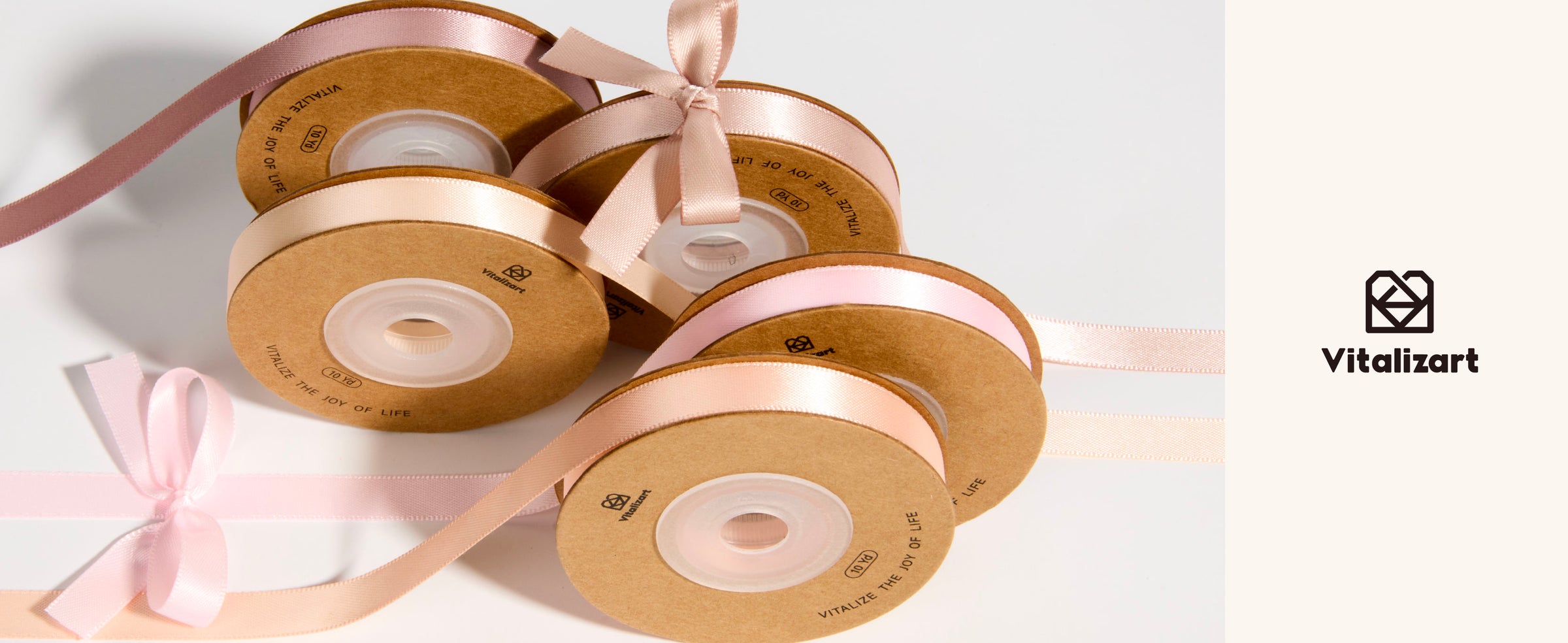 Five spools of blush, peach, cream, and dusty rose satin ribbon with loose lengths and small bows.