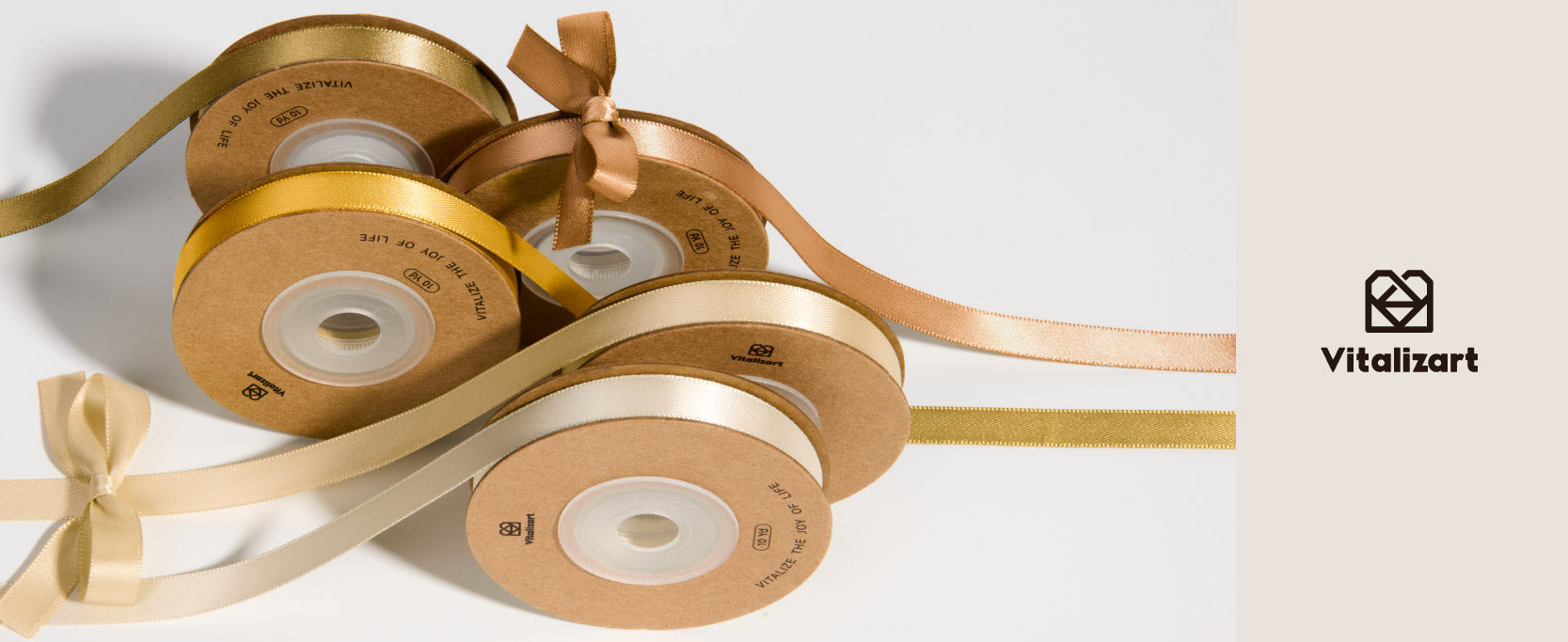 Five assorted gold satin ribbon spools in mustard, champagne, cream, and copper tones with bows.