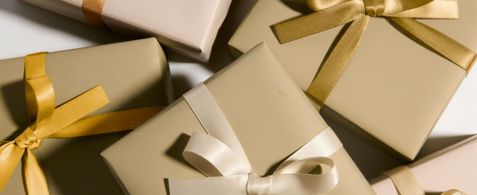 Kraft satin ribbon boxes and flat cardboard packaging pieces arranged on a sunlit wooden table