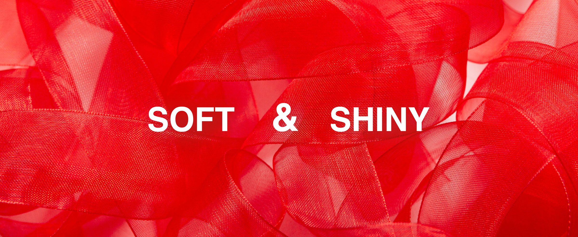 Close-up of soft, shiny red sheer ribbon arranged in overlapping translucent loops