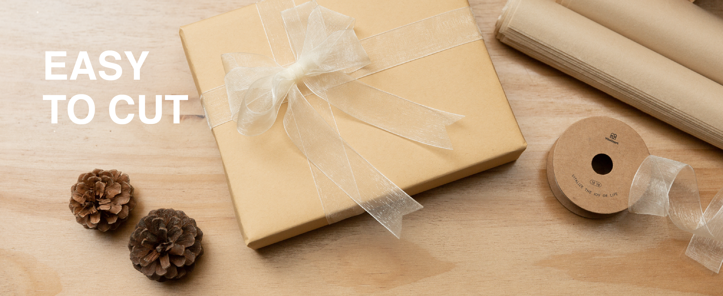 Ivory sheer organza ribbon tied in a layered bow on a kraft gift box beside scissors and a spool.