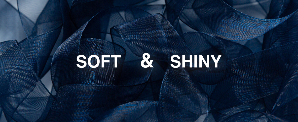 Navy-blue sheer organza ribbon in layered loops, showing its translucent weave and subtle shine.