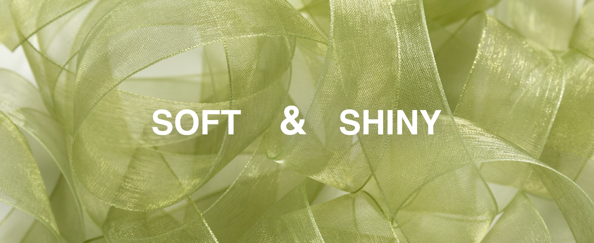 Close-up of soft, shiny sage green sheer organza ribbon arranged in loose loops.
