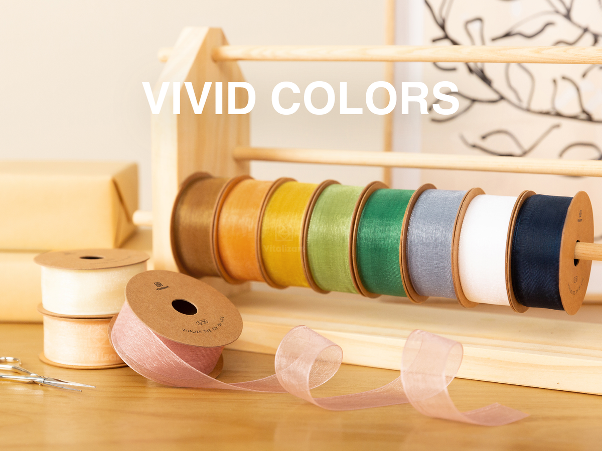 Sheer organza ribbon spools in assorted vivid colors displayed on a wooden rack and craft table