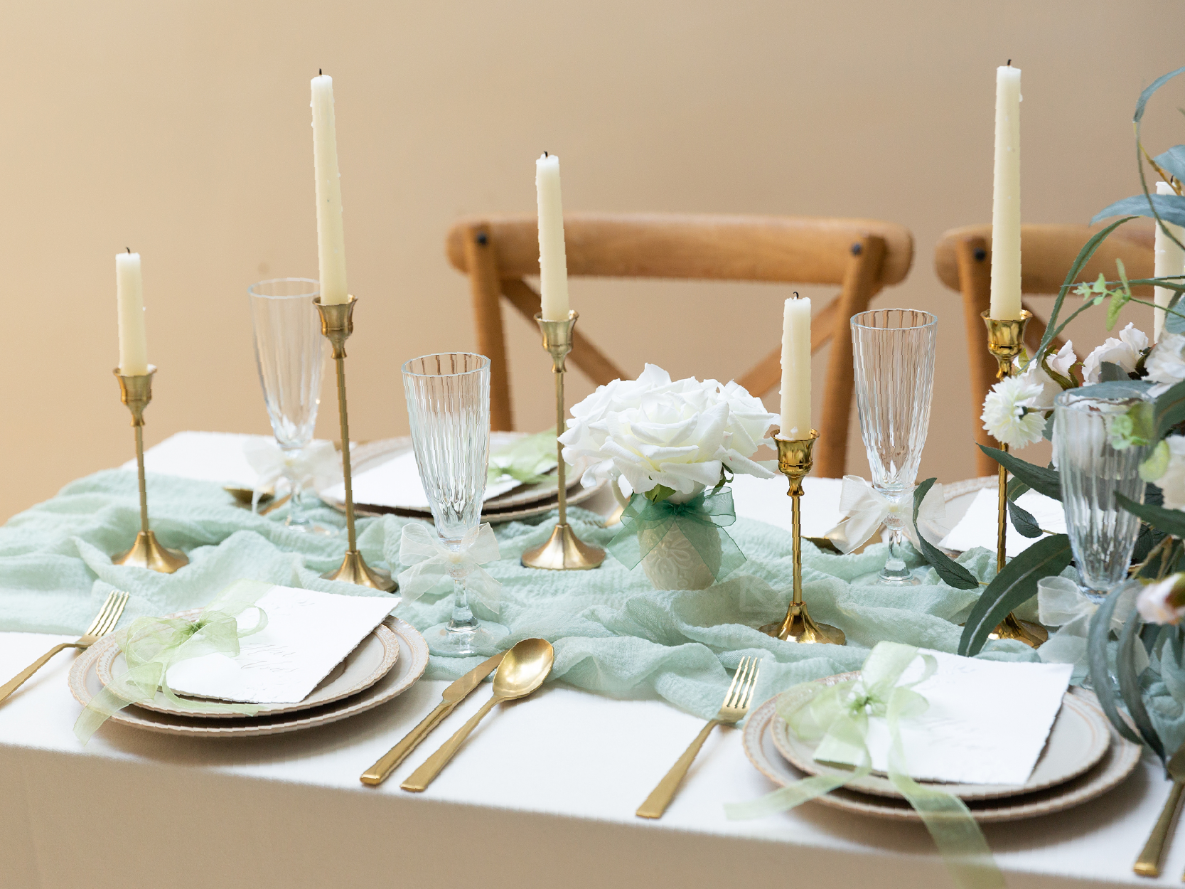 Green and white sheer ribbon bows decorate glasses, flowers, and place settings on an elegant table