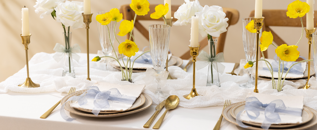 Pale blue sheer organza ribbon bows decorate napkins, glasses, and vases on a formal table
