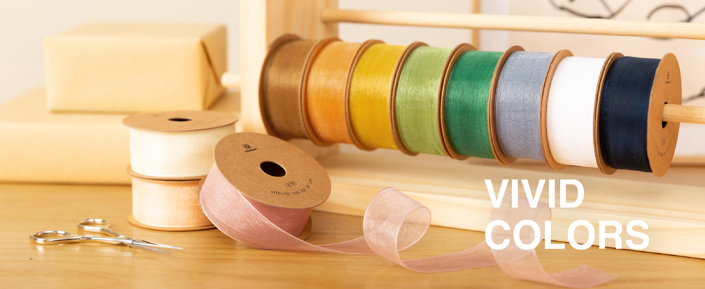Assorted sheer organza ribbon spools in vivid colors arranged on a wooden rack and craft table