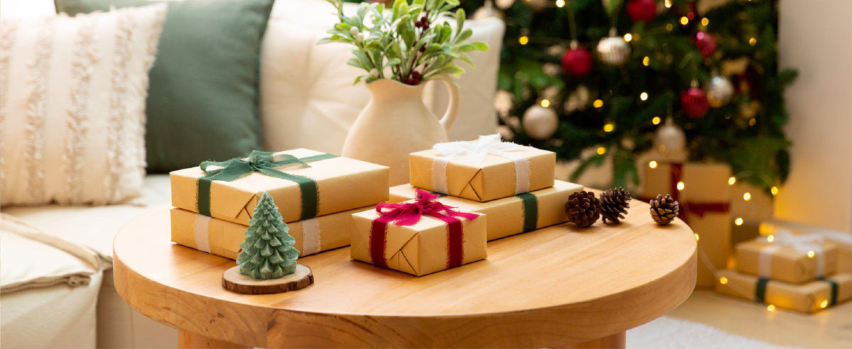 Deep red frayed-edge ribbon tied around a kraft-wrapped gift beside a matching roll