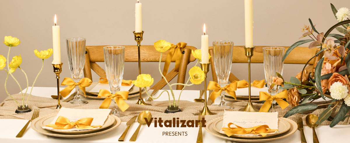 Gold satin-like ribbon bows decorate glasses, napkins and a chair at a candlelit dining table.