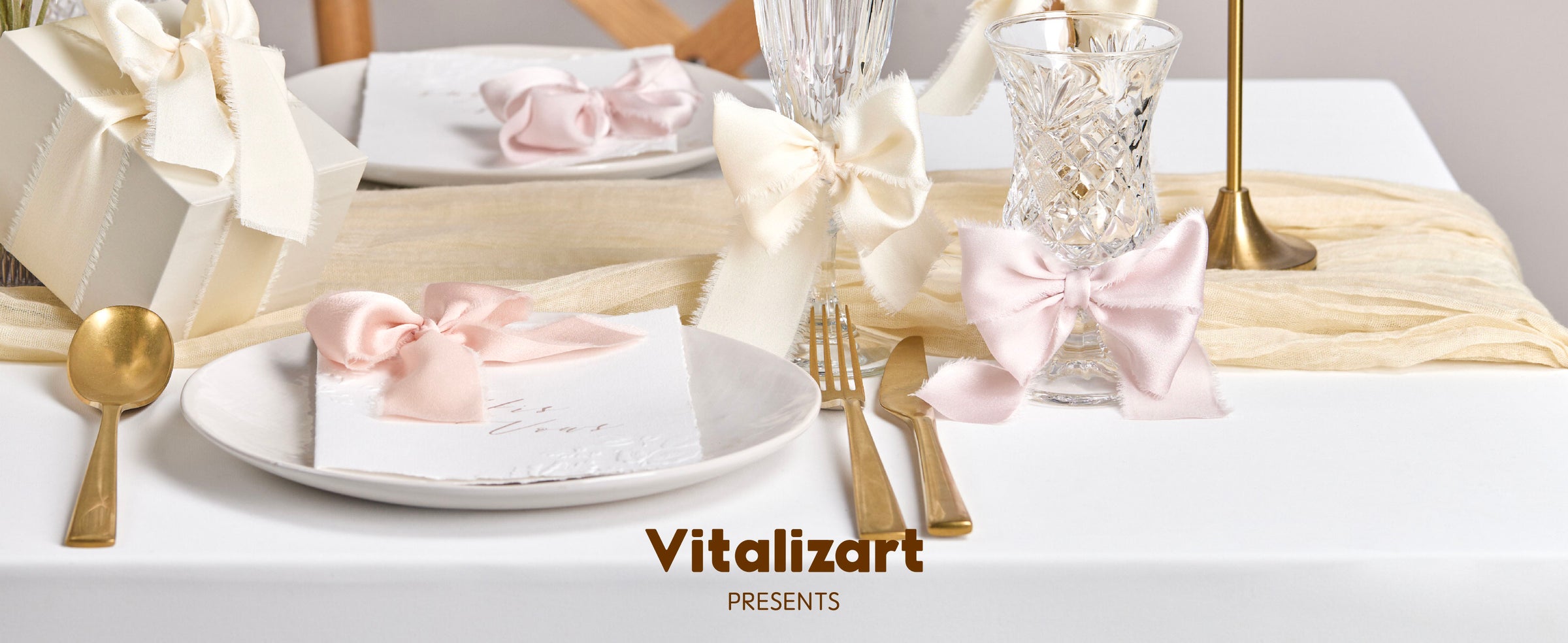 Cream frayed-edge ribbon bows decorate a gift, glass and candleholder on an elegant dining table.