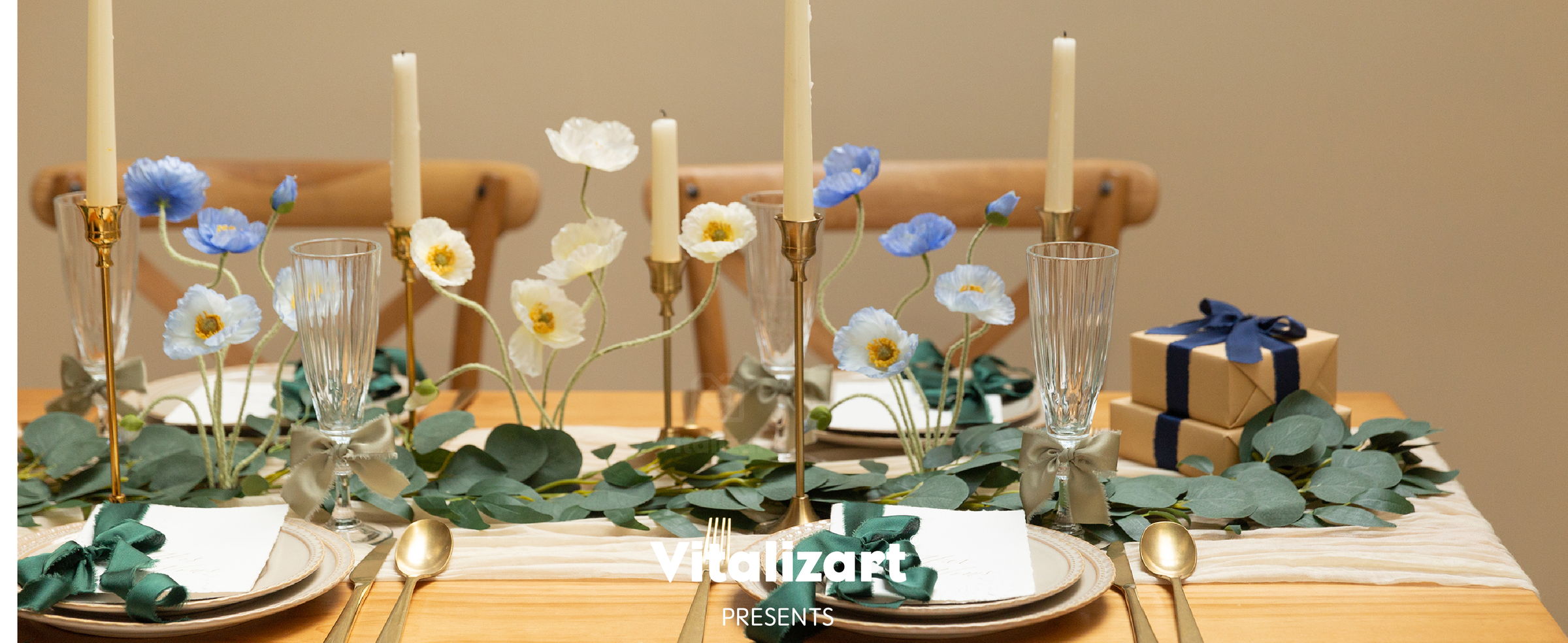 Navy ribbon wraps stacked kraft gifts on a formal table with flowers, candles, and gold flatware.