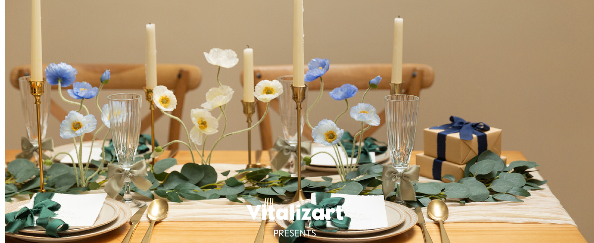 Dusty green ribbon bows decorate glasses on a candlelit table with flowers and greenery