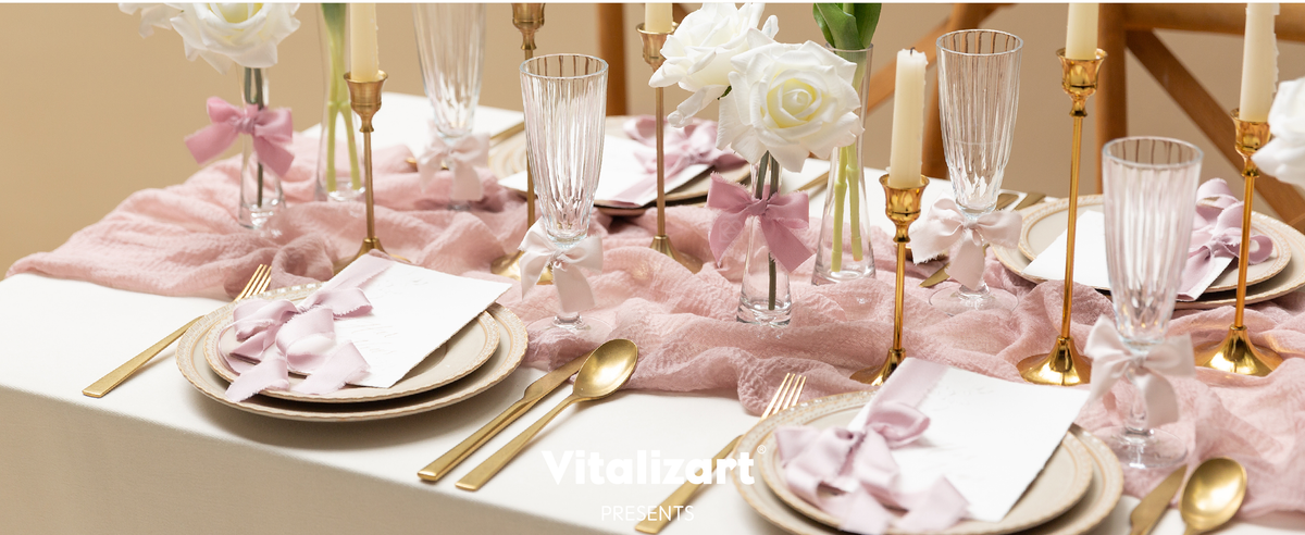 Pink and peach frayed satin bows decorate place cards, glasses, and flowers on an ivory table setting.