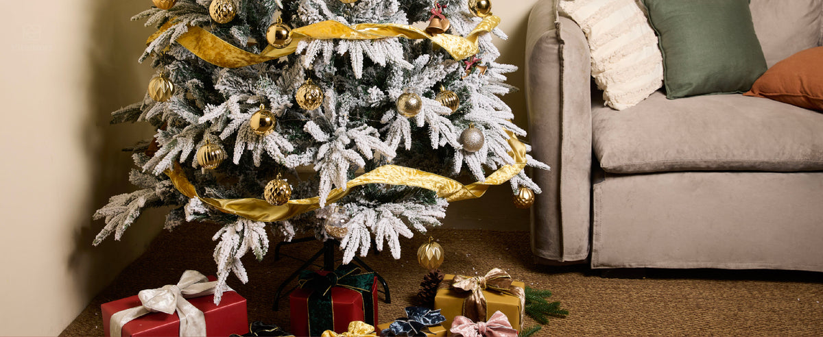 Gold wired velvet ribbon spiraling around a flocked Christmas tree with gold ornaments