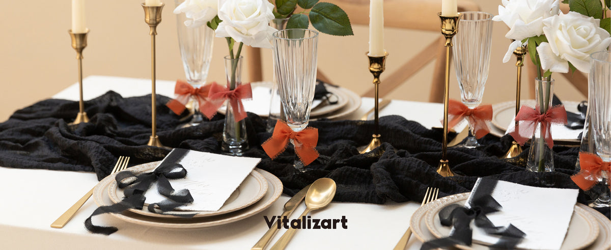 Black chiffon ribbon accents place cards on a candlelit table with roses and gold flatware