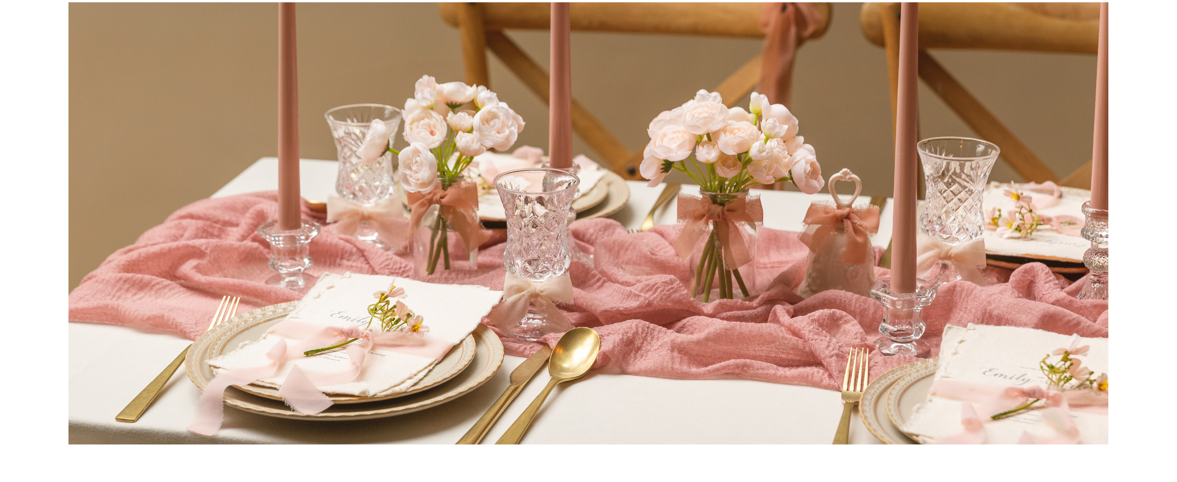 Dusty rose chiffon ribbon decorates place cards, vases, glasses, and chairs on a candlelit table