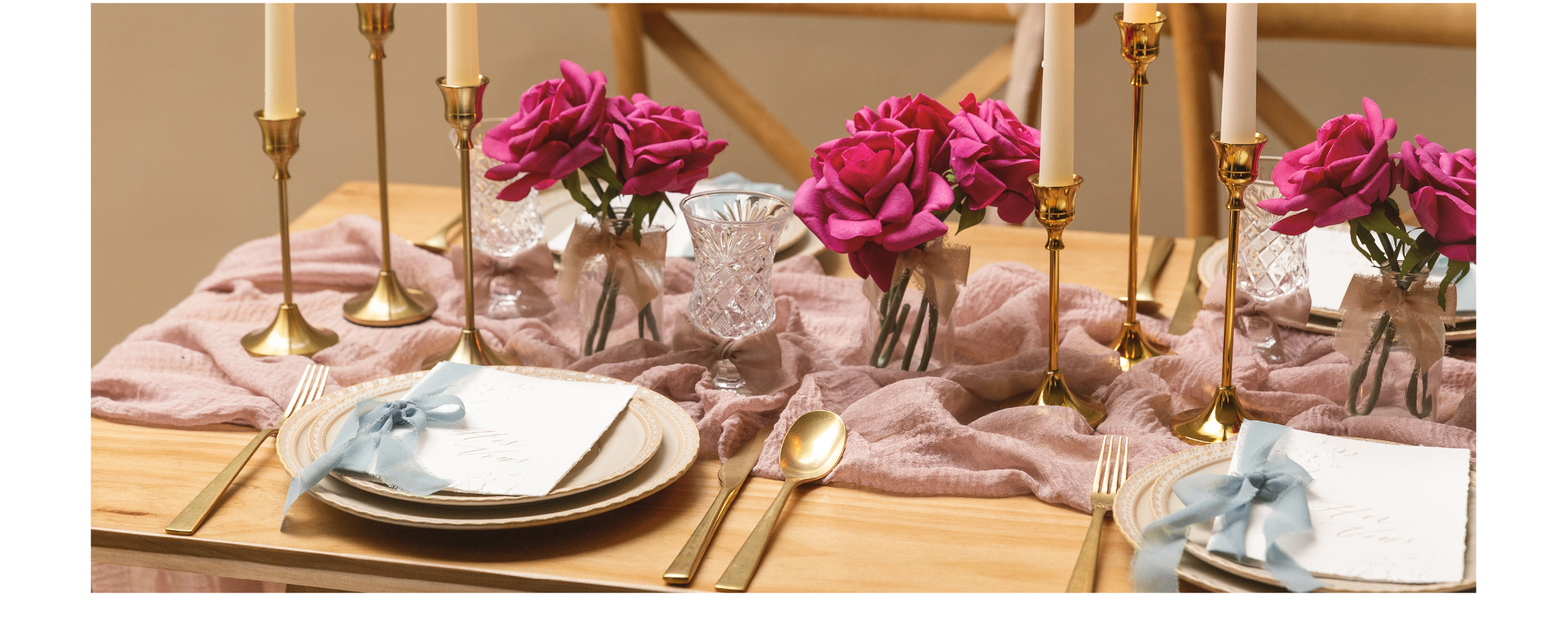 Blush and blue chiffon ribbons decorate place cards and rose vases on a candlelit dinner table