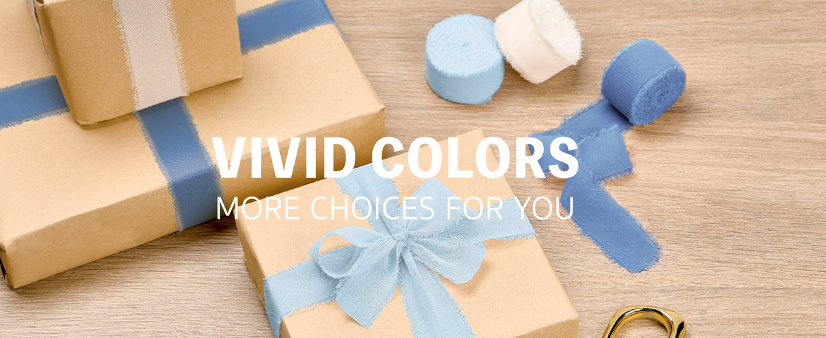 Kraft gifts wrapped with ivory, baby blue, and dusty blue chiffon ribbon beside rolls and gold scissors.